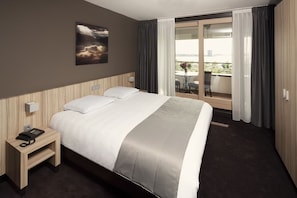 Relax in a spacious room with a large bed, telephone, and a window offering a view of the outdoors.