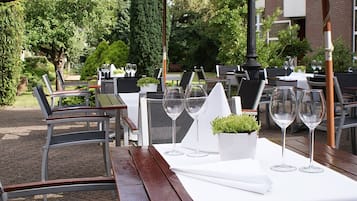 Enjoy a serene dining experience amidst lush greenery under shaded umbrellas.