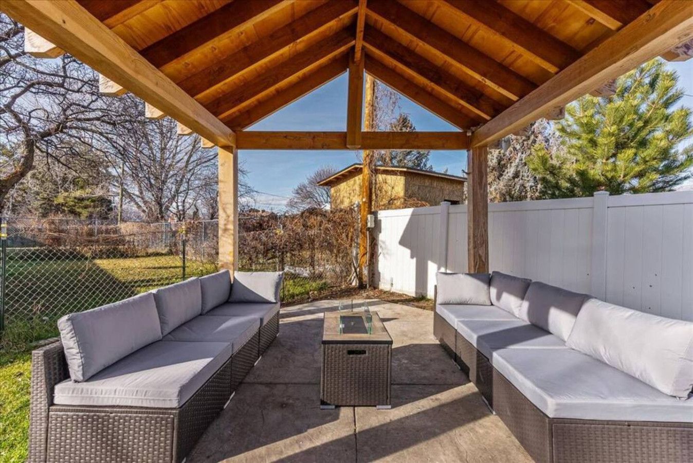En udendørs terrasse med fletmøbler og et pergola-laug.