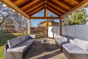 An outdoor patio with wicker furniture and a pergola.