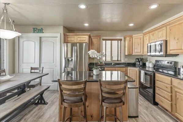 A modern kitchen with wooden cabinets, stainless steel appliances, and a central island with bar stools.