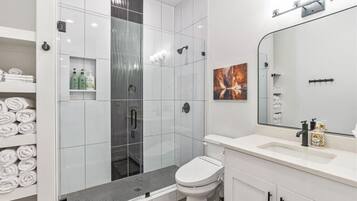 A modern bathroom with a glass shower enclosure, a white toilet, and a vanity with a mirror.