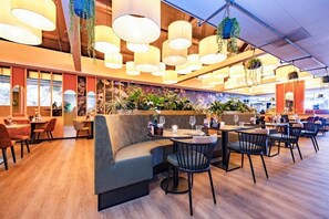 Enjoy a warm and inviting dining experience with a curved bench and individual tables amidst a beautifully lit space.