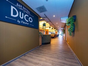 Welcome to the hotel's inviting interior corridor, featuring a reception desk and lush greenery.