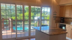 A spacious kitchen with a large island, wooden flooring, and a view of a pool through glass doors. - Waterfront Key West Style Home (Ellenton)