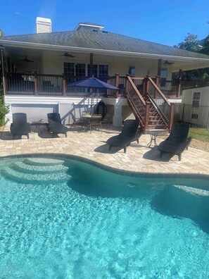 A swimming pool with lounge chairs and a covered patio area.