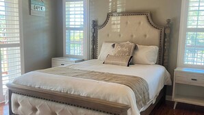 A bedroom with a large bed, wooden flooring, and two nightstands. - Waterfront Key West Style Home (Ellenton)