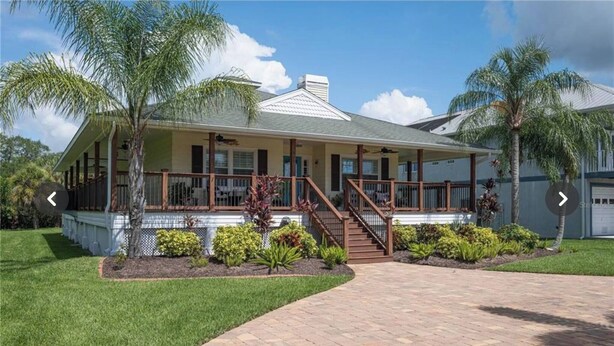 A two-story house with a covered porch, a staircase leading to the upper floor, and a well-maintained lawn. - Waterfront Key West Style Home (Ellenton)