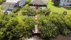 An aerial view of a residential property with a large house, a swimming pool, and a dock extending into a body of water. - Waterfront Key West Style Home (Ellenton)