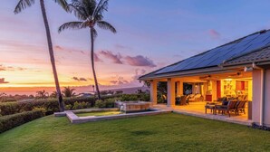Une maison dotée d’un patio couvert, d’un espace salon extérieur et d’un petit élément décoratif aquatique.