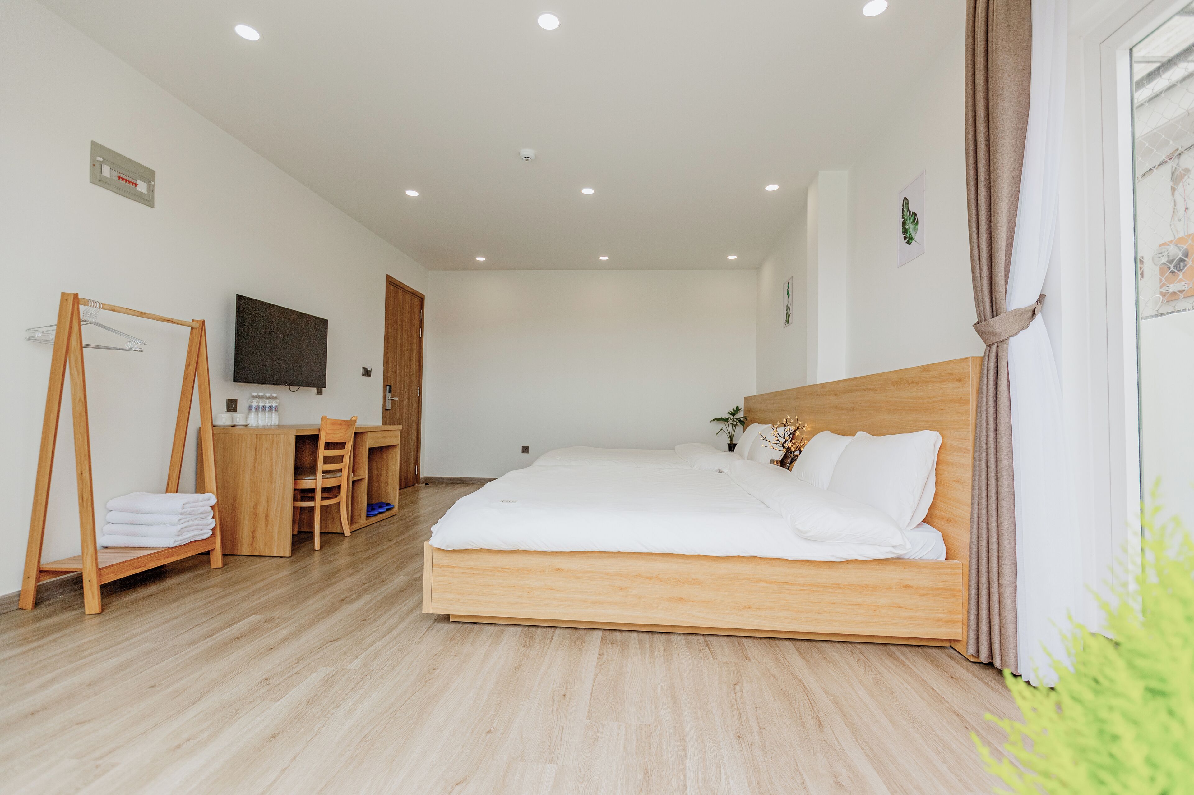 A modern bedroom with a wooden bed, a desk, and a television.