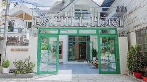 Exterior del Hotel DAHILL con una entrada verde, un letrero y el número de la calle visible.