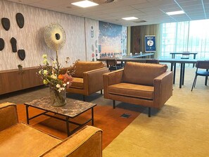 Relax in our inviting lobby, featuring comfortable seating, a beautiful floral arrangement, and a stunning wall art piece.