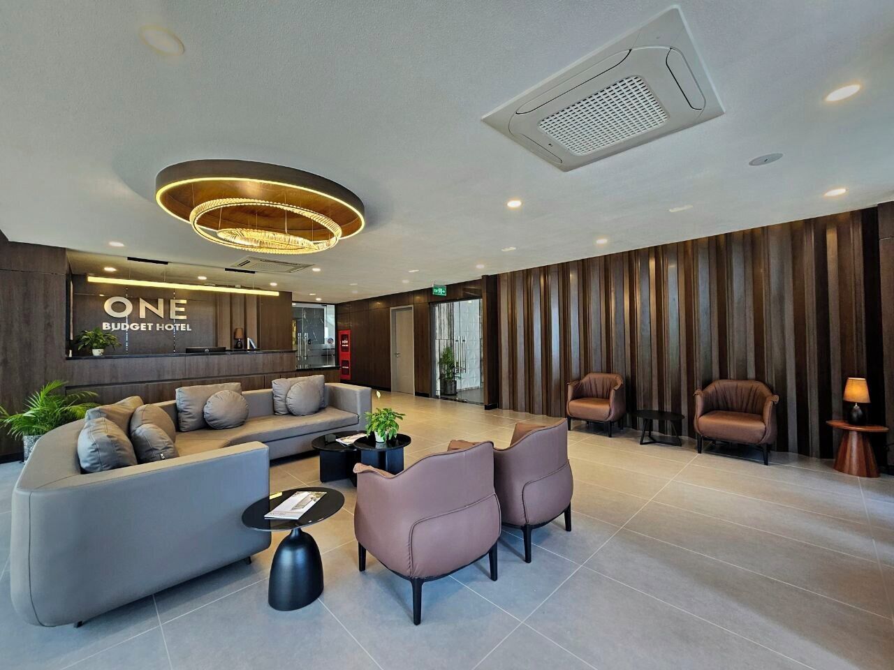 A modern lobby with a sofa, armchairs, a coffee table, and a reception desk.