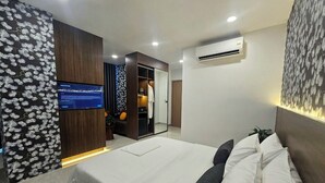 Une chambre moderne avec un grand lit, une armoire, un téléviseur et un appareil de climatisation.