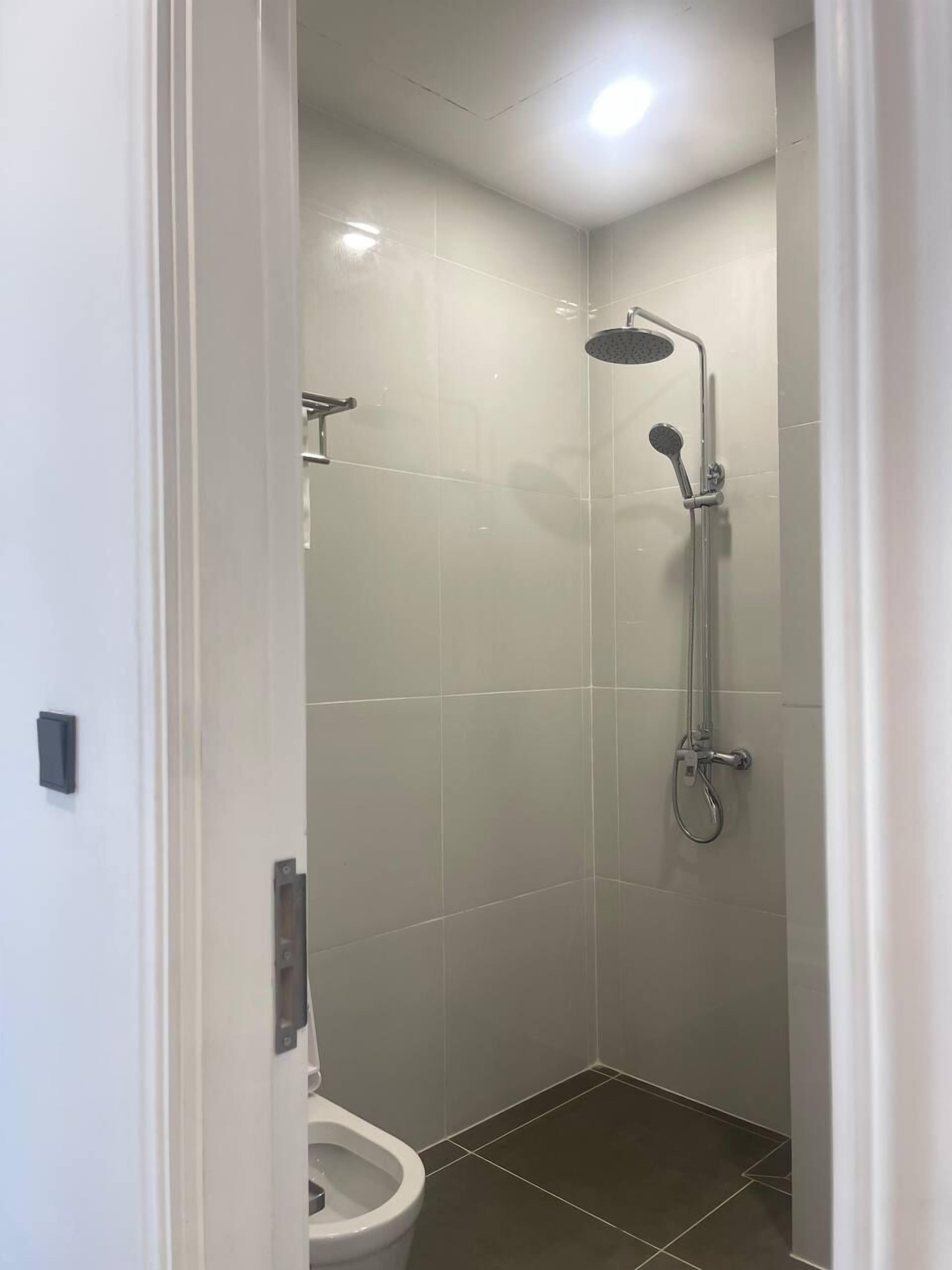 Een kleine, moderne badkamer met douche, toilet en een lamp aan het plafond.