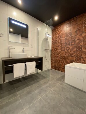 Enjoy a refreshing shower or soak in the bathtub in this bathroom, featuring a glass-enclosed shower and a separate bathtub.