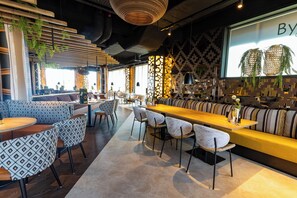 Relax with a drink at the hotel's stylish bar, featuring a long bar and comfortable seating options.