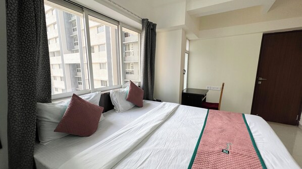 Une chambre d’hôtel avec un lit, un bureau et une fenêtre avec des rideaux.