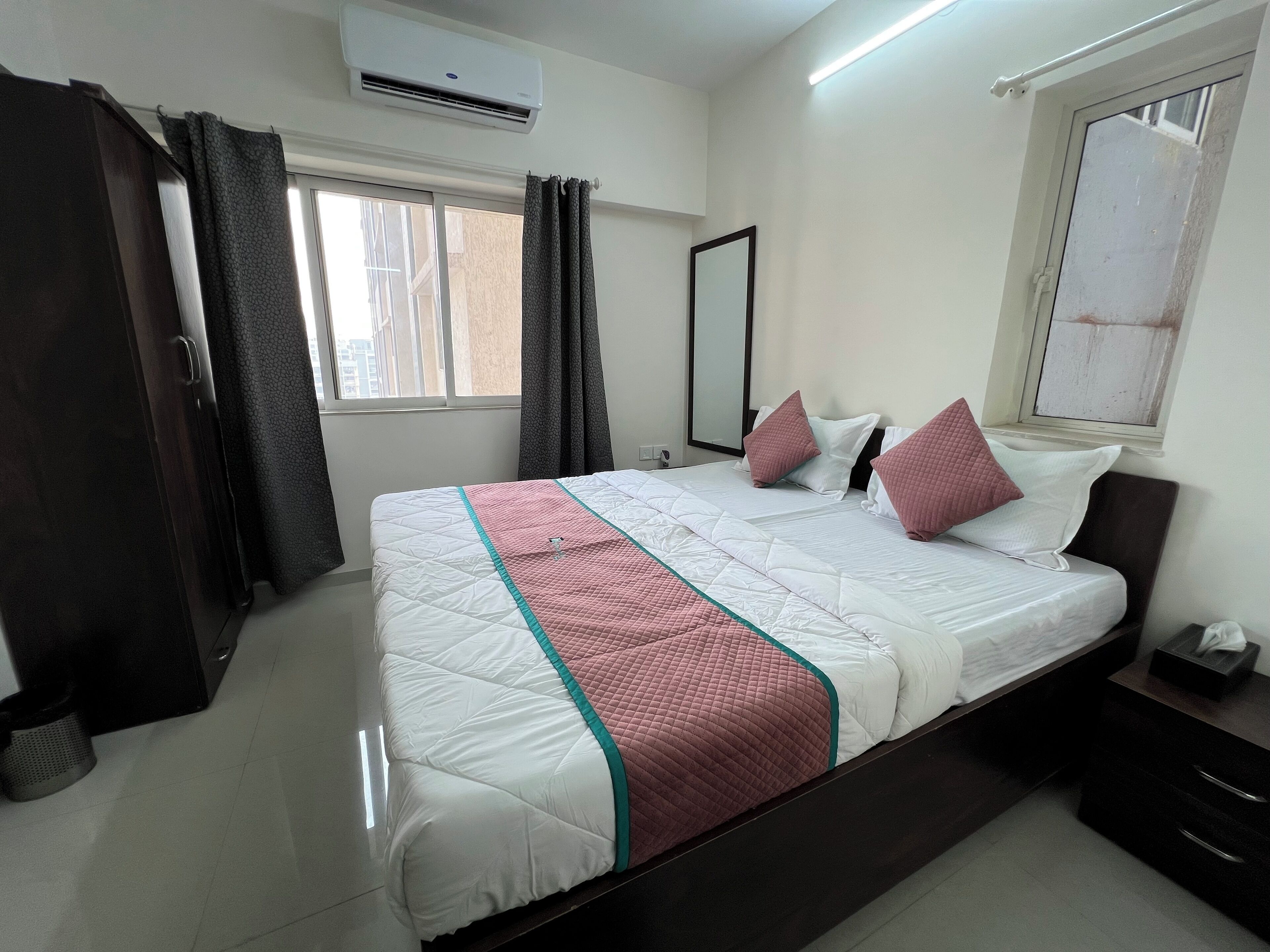 Habitación de hotel con una cama grande, una mesita de noche, un espejo y un equipo de aire acondicionado.