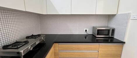 Una cocina compacta con estufa a gas, microondas y armarios de madera.