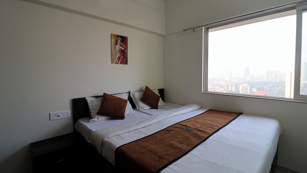 Quarto de hotel com uma cama, uma janela com vista para a cidade e um quadro na parede.