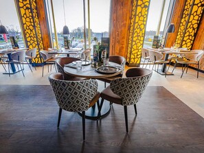 Enjoy meals in a stylish dining area with a central table, comfortable chairs, and large windows offering a view.