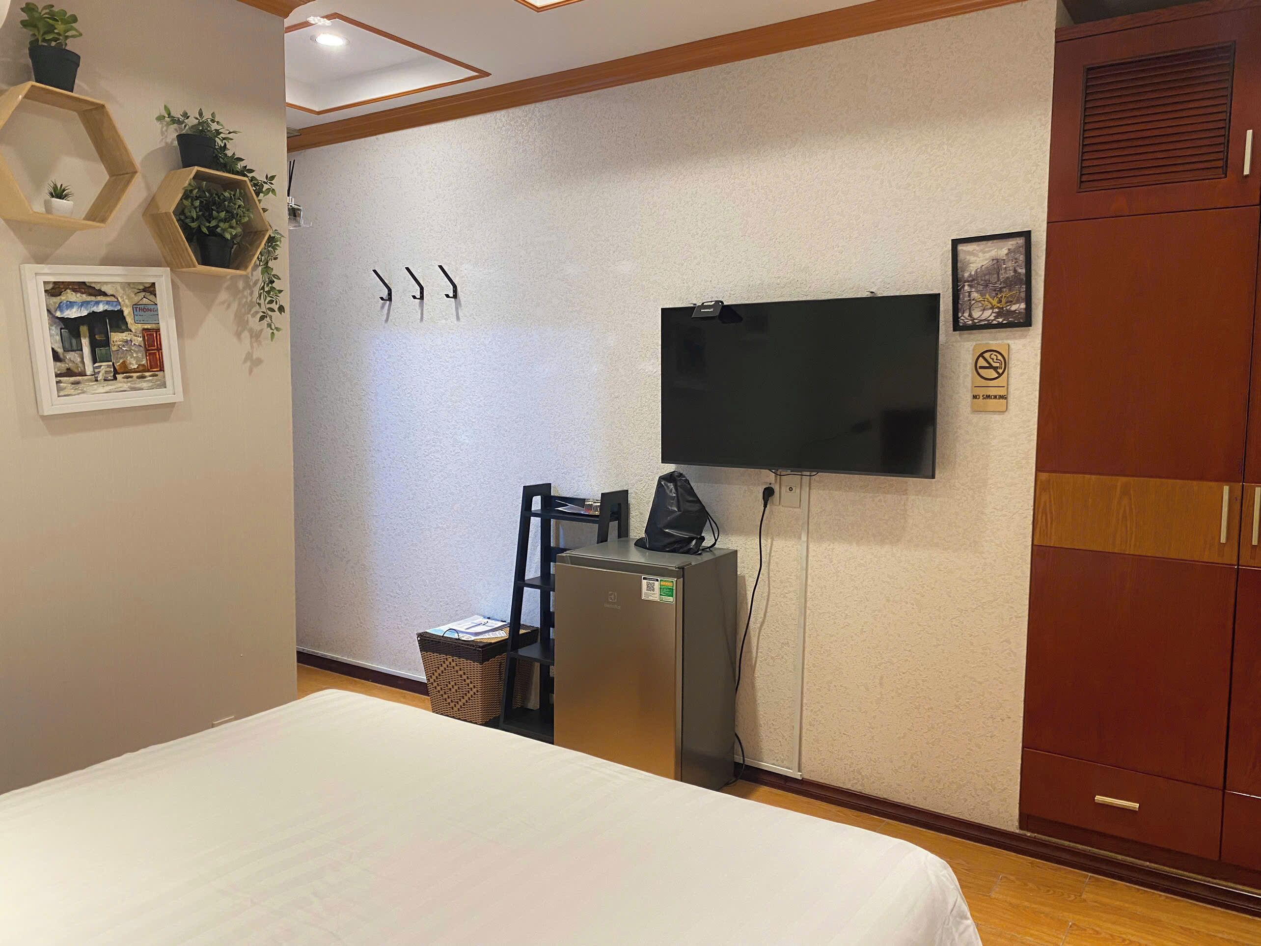 Una camera d'albergo con un letto, una scrivania con un computer, una televisione a parete e un armadio.