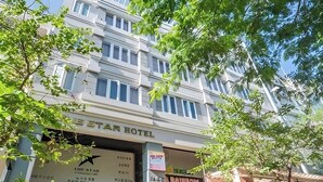 Un hotel con letrero, mesas al aire libre y plantas en macetas.