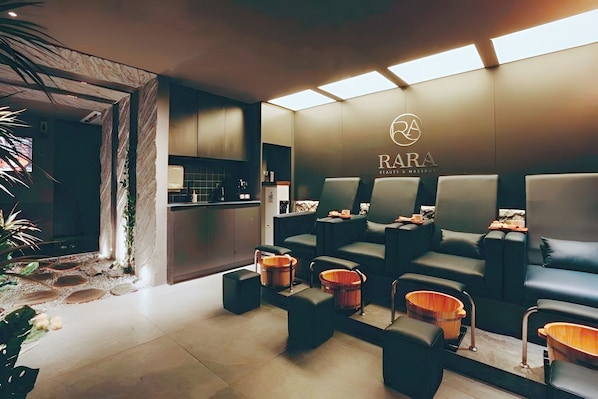 A spa area with seating, a reception desk, and a logo on the wall. - The Star Hotel - Phu My Hung (Ho Chi Minh City)
