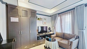 Una sala de estar moderna con un sofá, un televisor, una mesita y un armario.