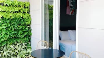 Una habitación con cama, ventana y una pequeña mesa con sillas.