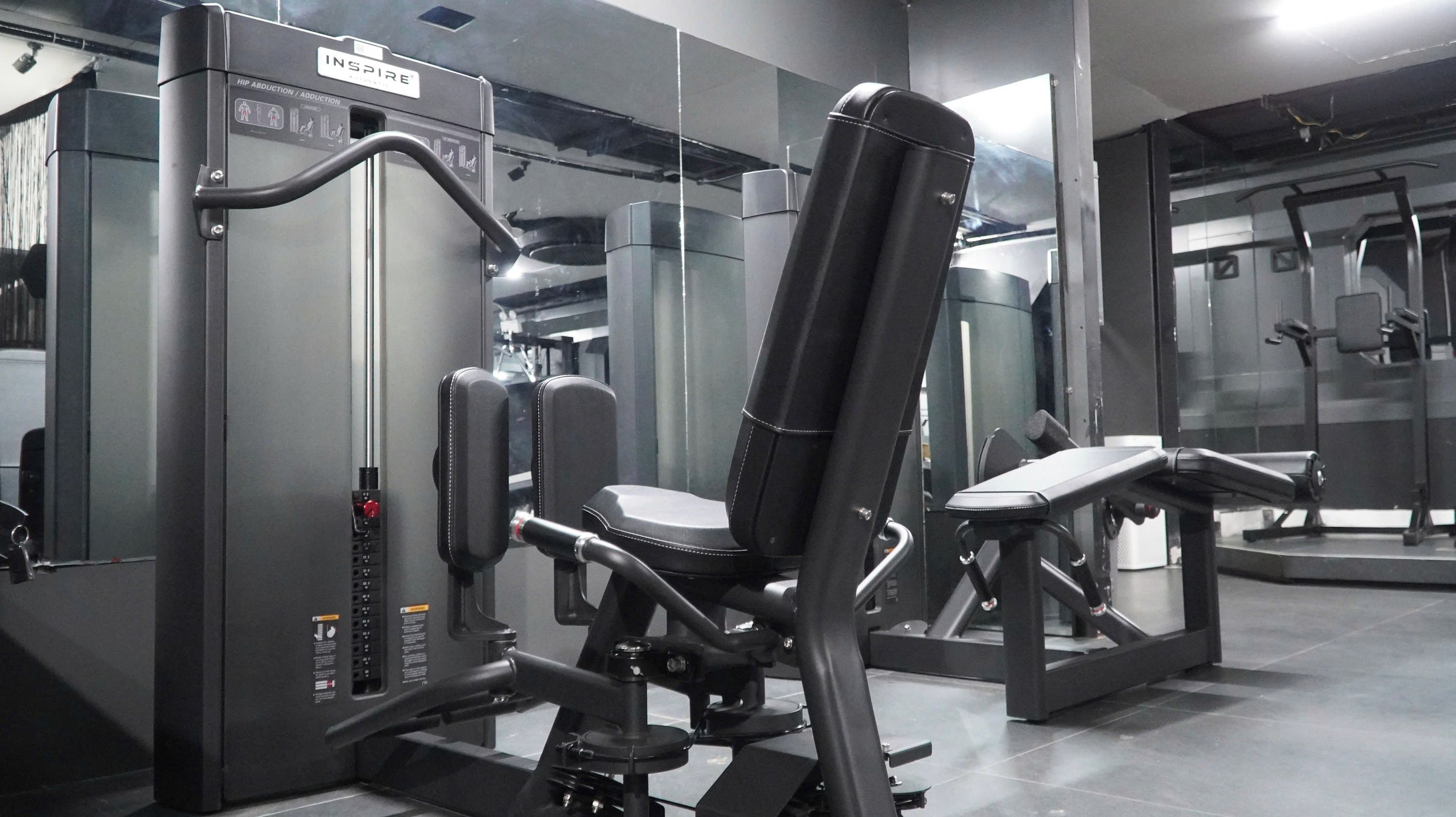 Une salle de sport équipée de matériel d’exercice, notamment une machine à presses pour les jambes et un banc.