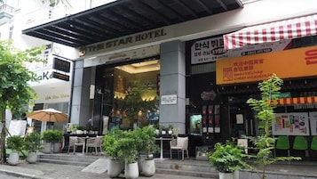 Entrada de hotel con asientos al aire libre y plantas en macetas.