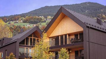 A modern building with a wooden facade and a balcony with outdoor seating.