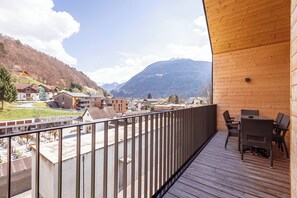 A wooden deck with outdoor furniture overlooking a mountainous landscape. - Montafon Suites Schruns by ALPS RESORTS (Schruns)