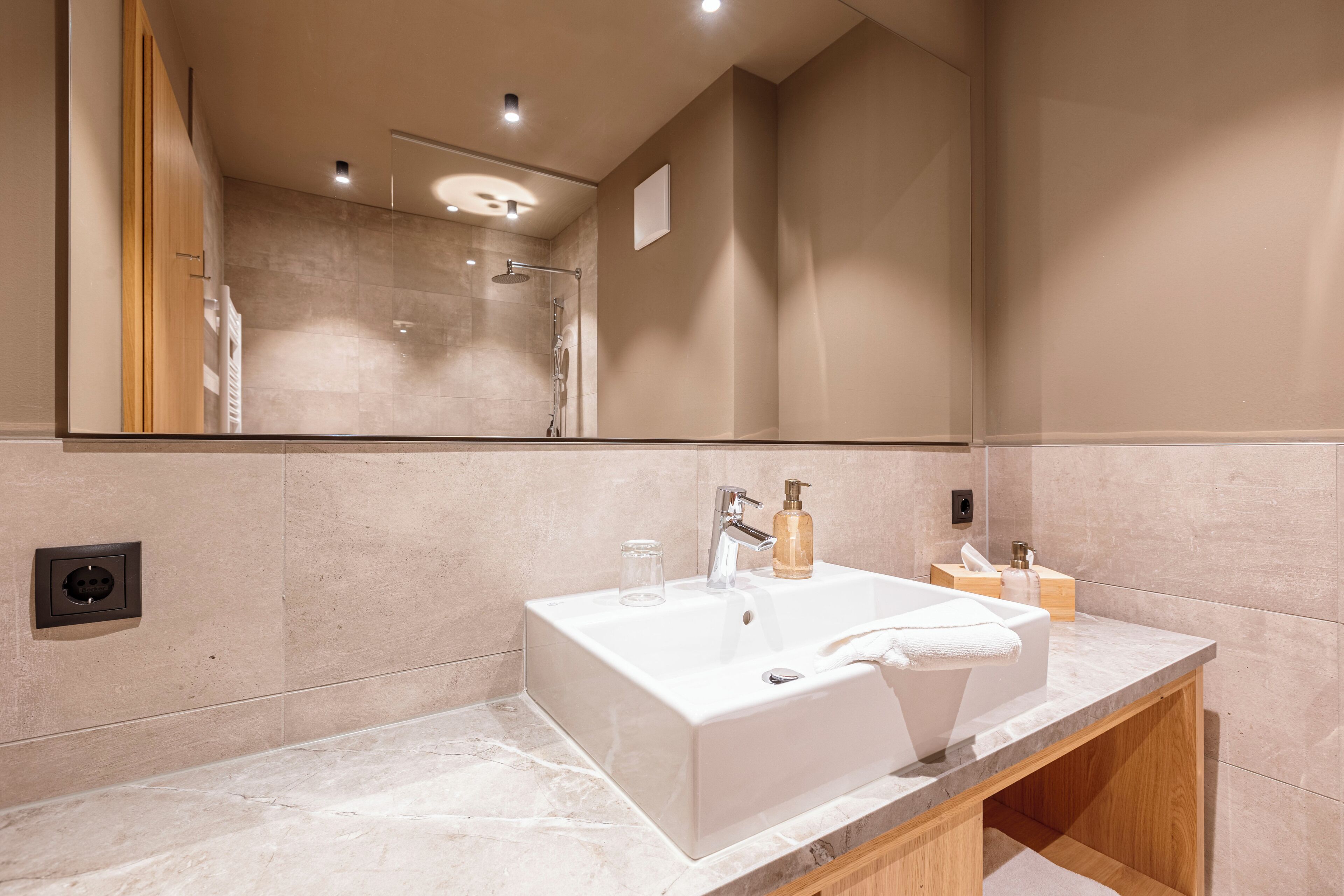 Un baño moderno con un lavabo grande de color blanco, un espejo y una zona de ducha.