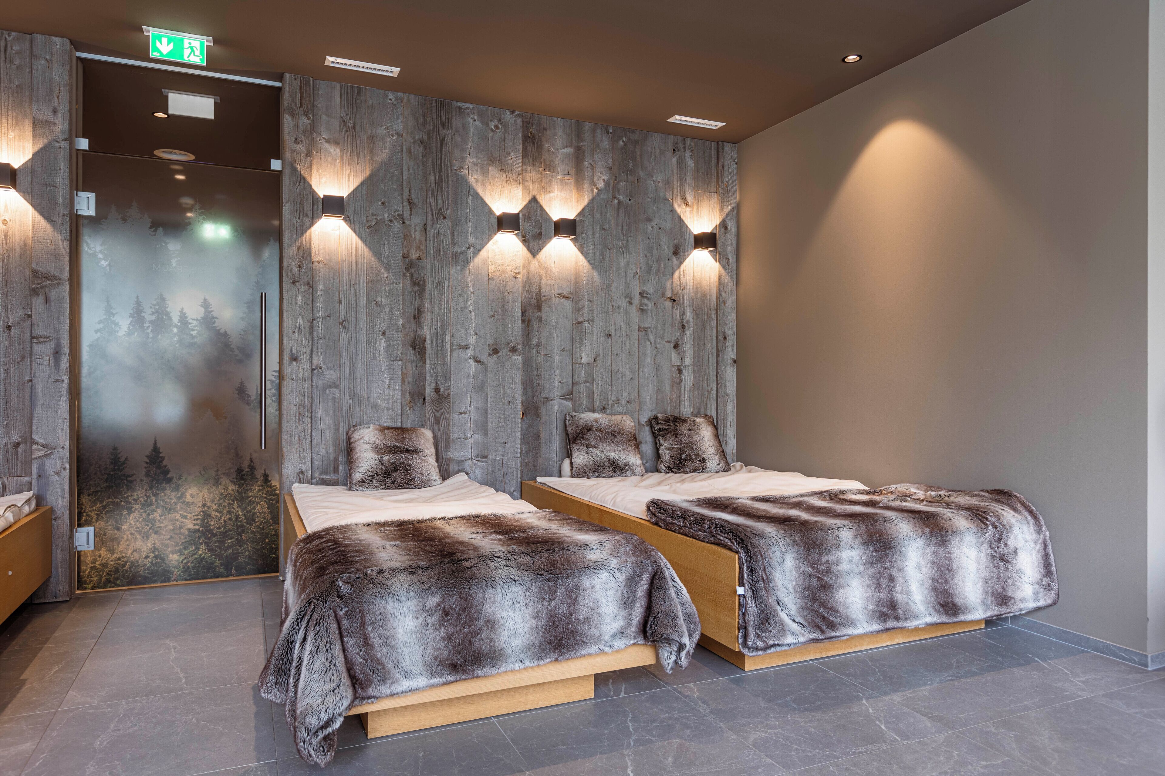 Un dormitorio moderno con dos camas, cabecero de madera e iluminación empotrada.