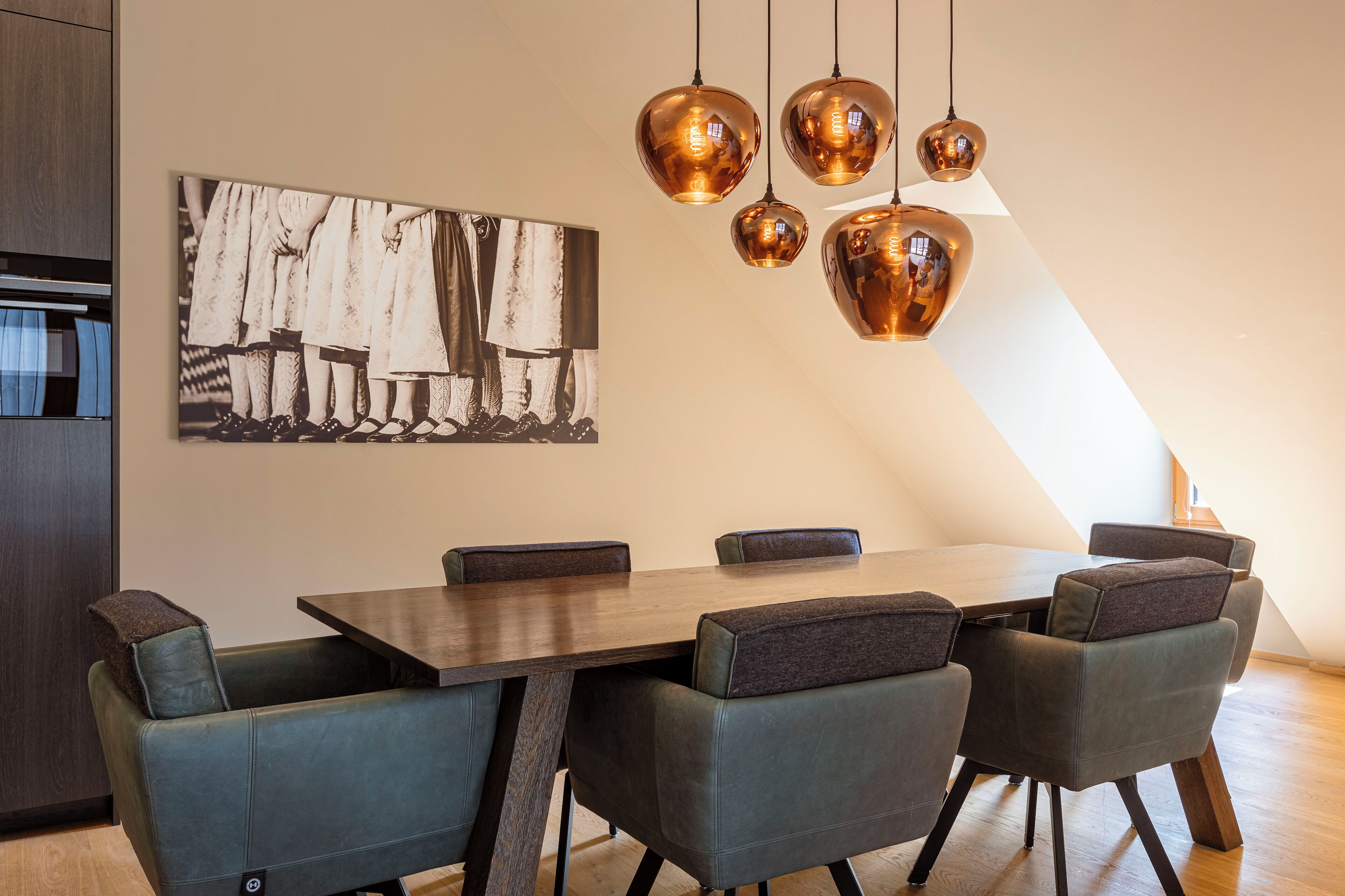 Un espace repas moderne avec une table en bois, six chaises rembourrées et un grand tableau abstrait accroché au mur.