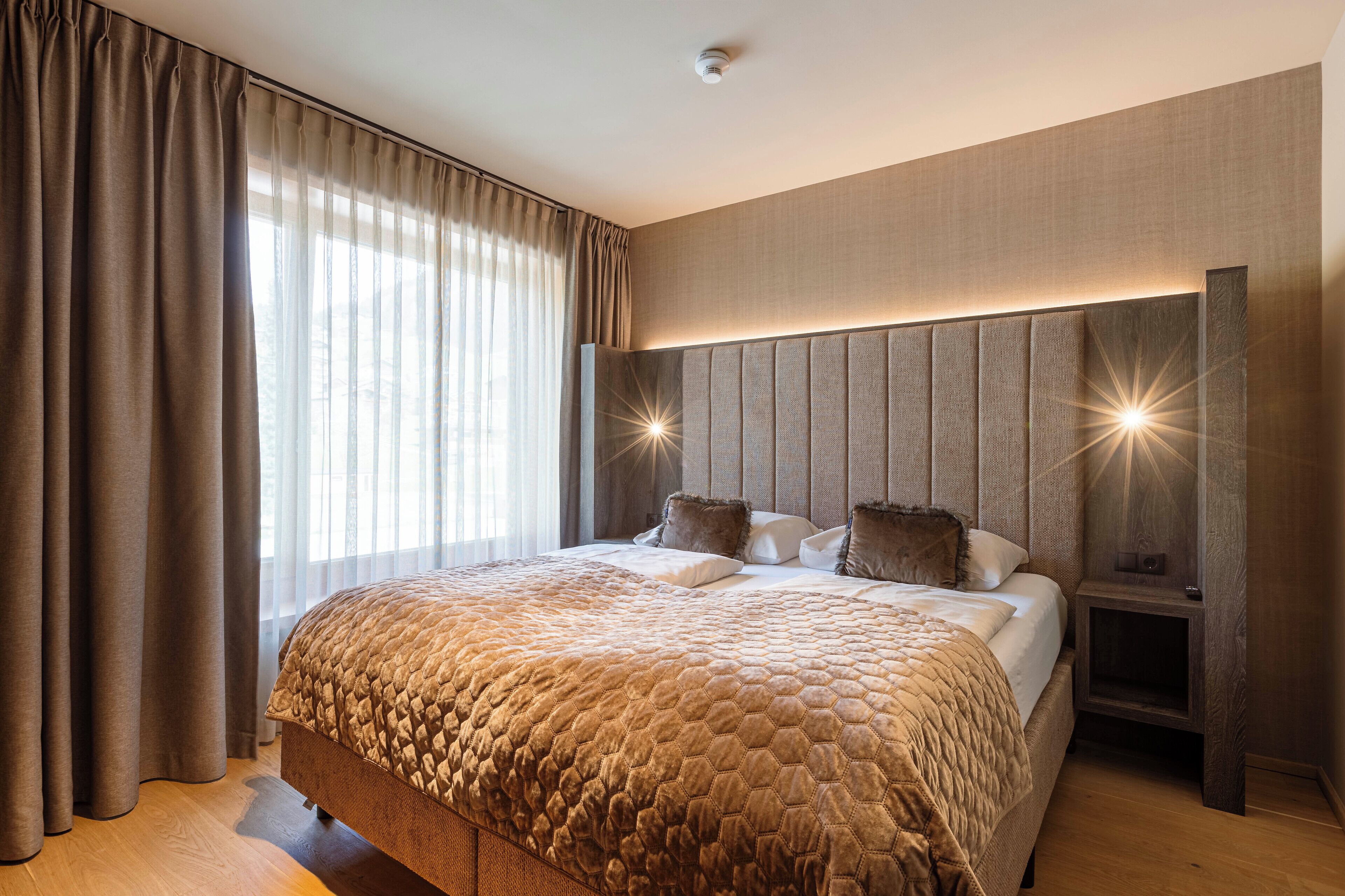 Ein modernes Schlafzimmer mit einem großen Bett, einer Kopfteilbeleuchtung und einem Nachttisch.