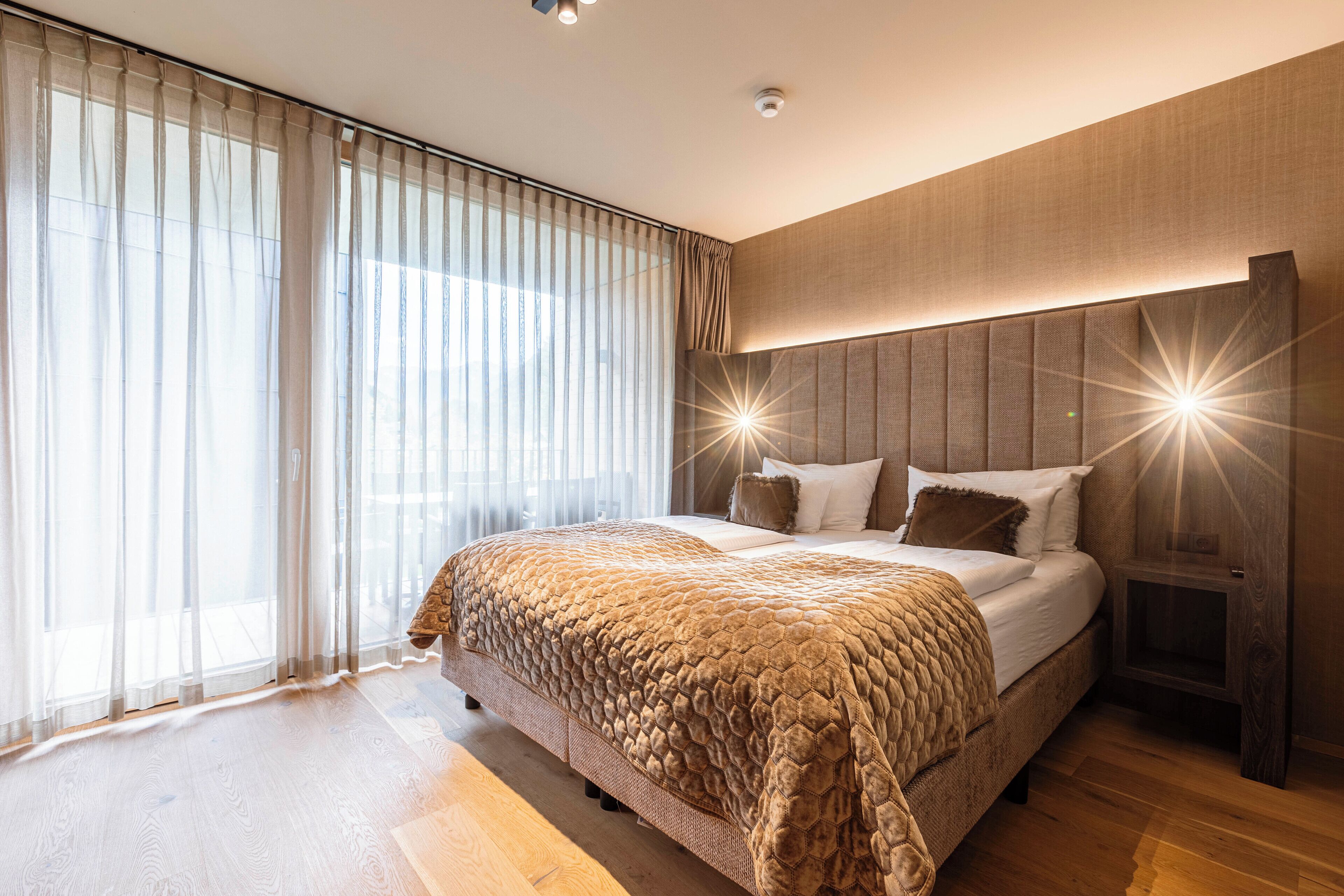 Une chambre à coucher moderne avec un grand lit, une table de chevet et un luminaire fixé au mur.