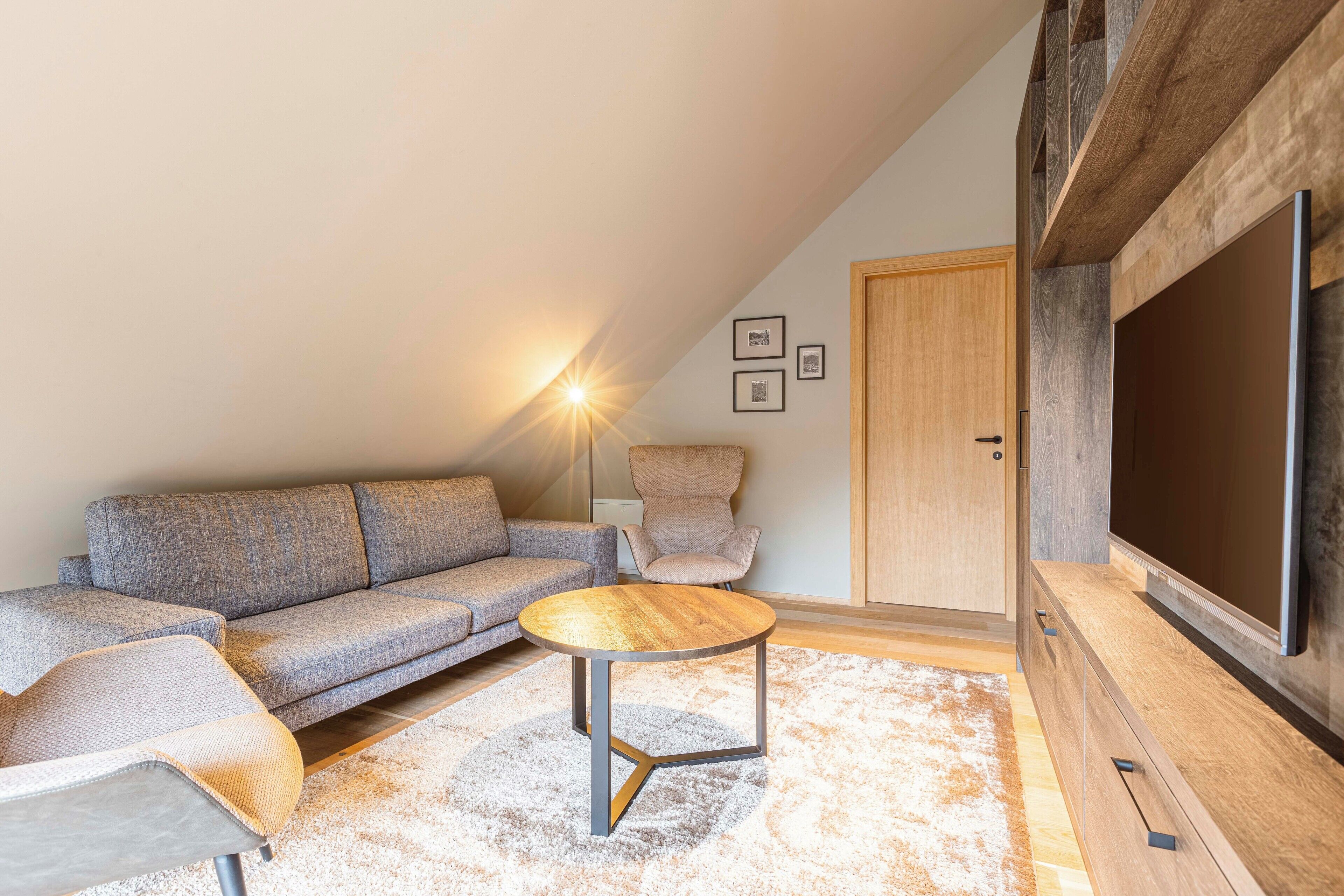 A modern living room with a sofa, armchairs, a coffee table, and a flat-screen TV.