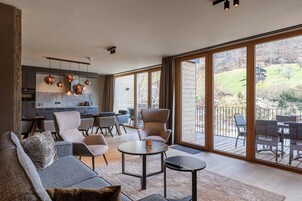 Un amplio salón con cocina moderna, asientos cómodos y grandes ventanales con vistas al exterior.