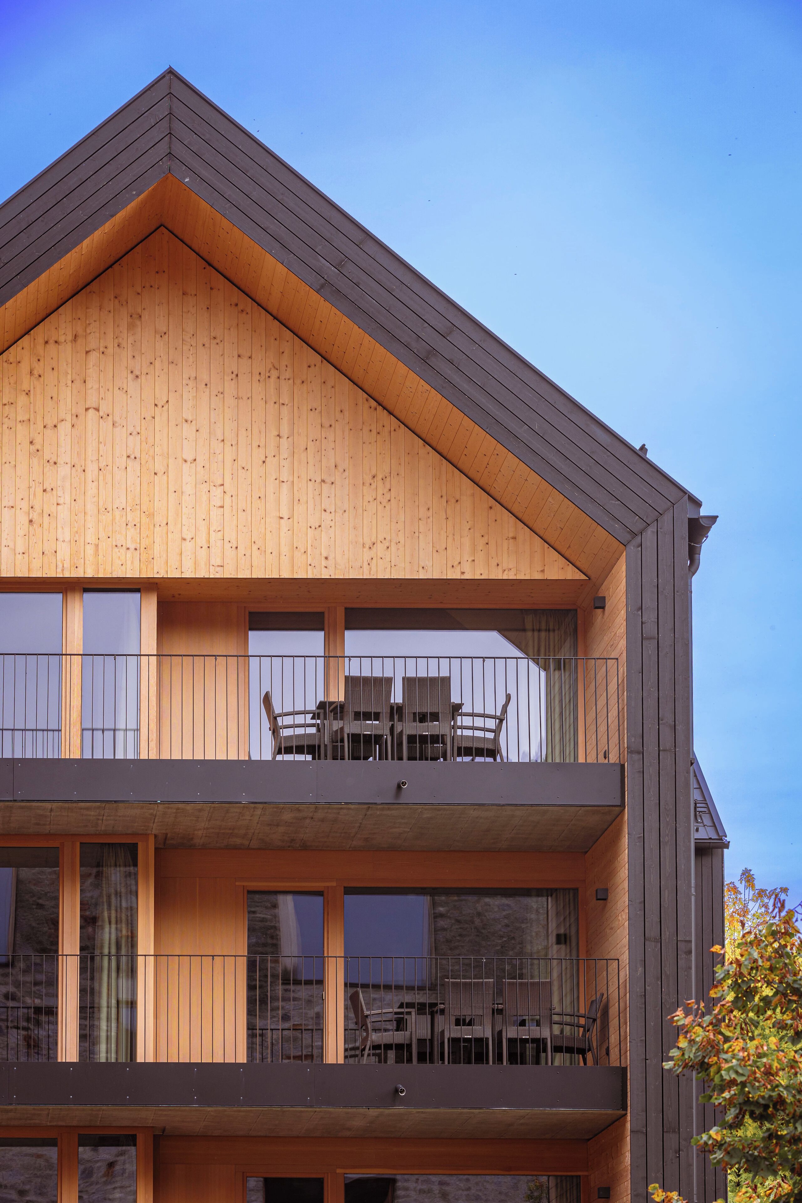 A multi-story building with a wooden facade, balconies with railings, and large windows.