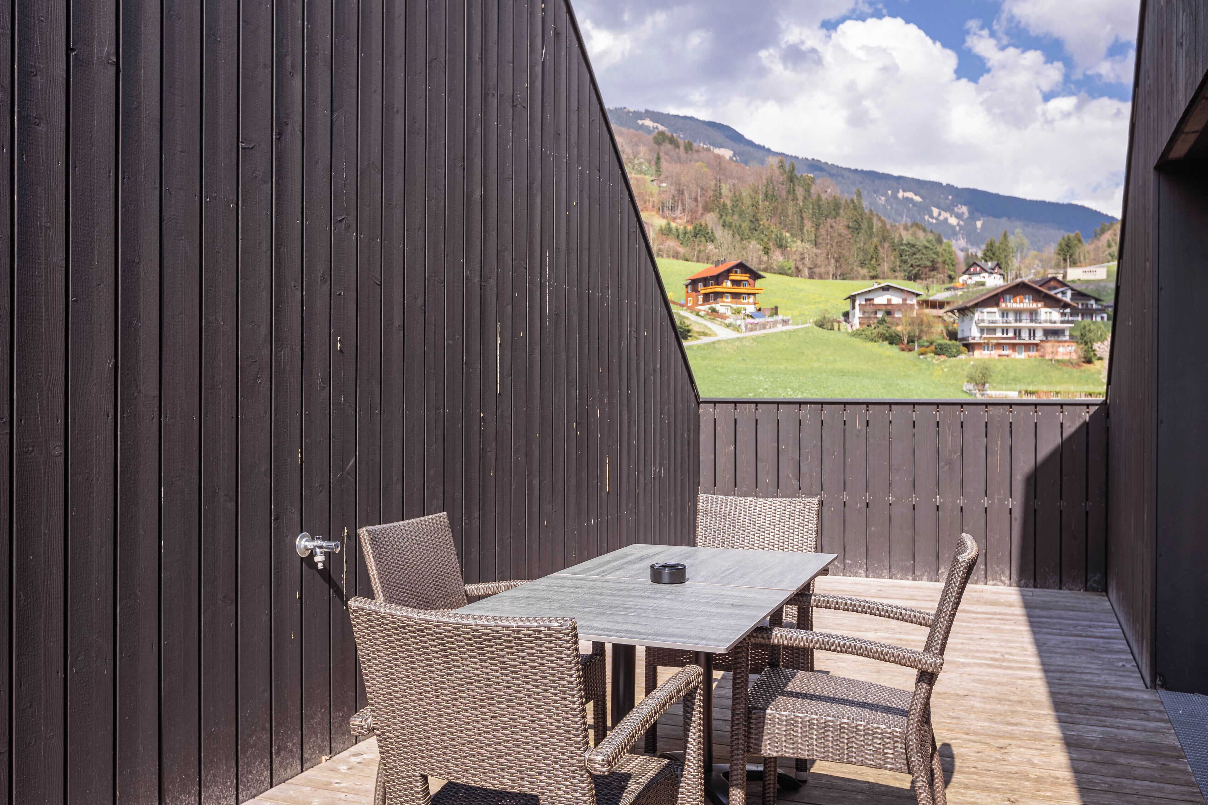 An outdoor patio with wicker furniture and a view of houses in the background.