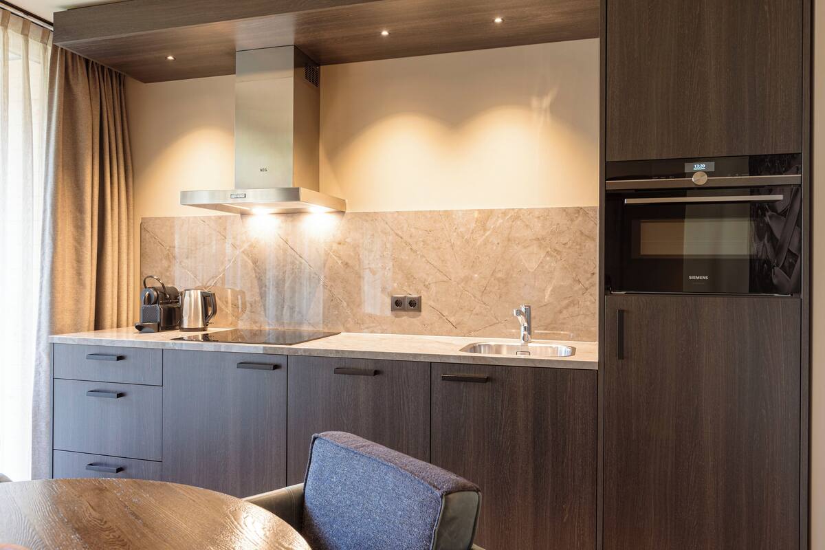Una cocina moderna con armarios de madera oscura, un lavamanos de acero inoxidable y un horno empotrado.