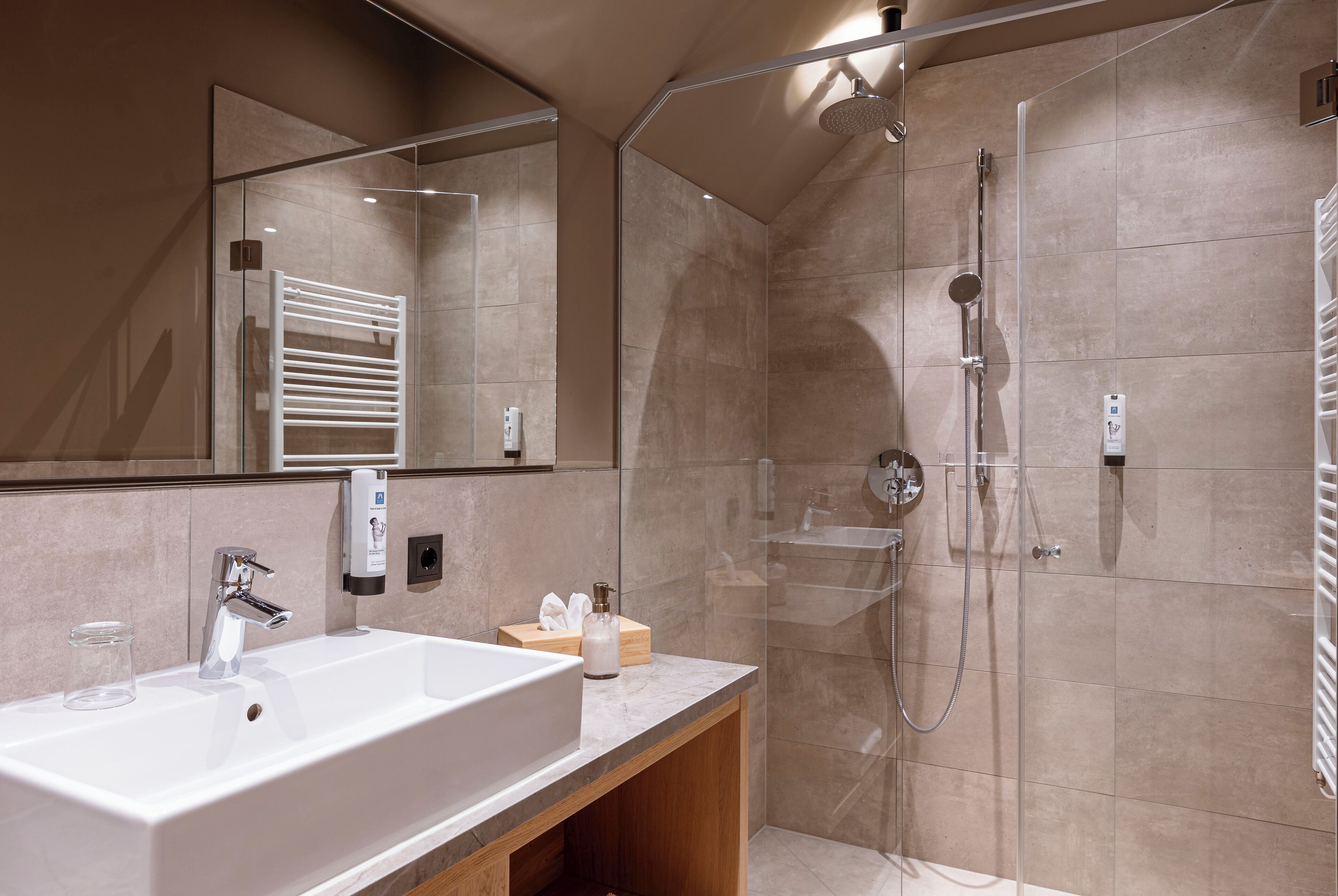 Ein modernes Badezimmer mit einem großen, weißen Waschbecken, einer Duschkabine aus Glas und einem hölzernen Waschtisch.