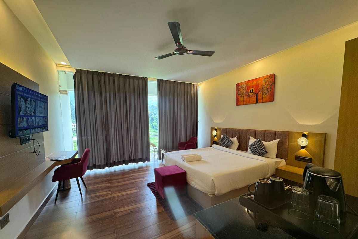 A hotel room with a bed, a desk, a chair, a TV, and a painting.