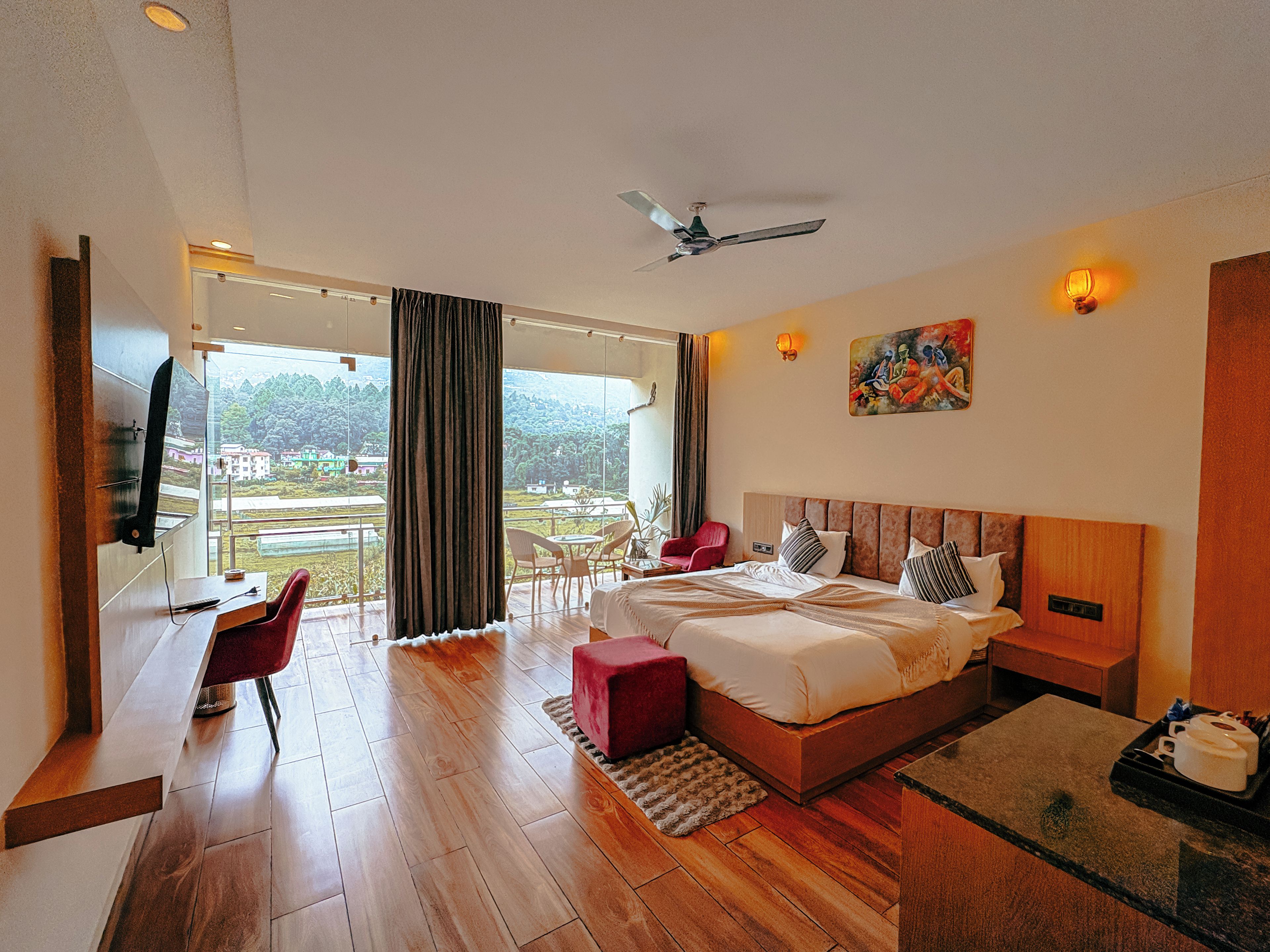 Ein Hotelzimmer mit Bett, Schreibtisch, Stuhl, Fernseher und Blick ins Freie.