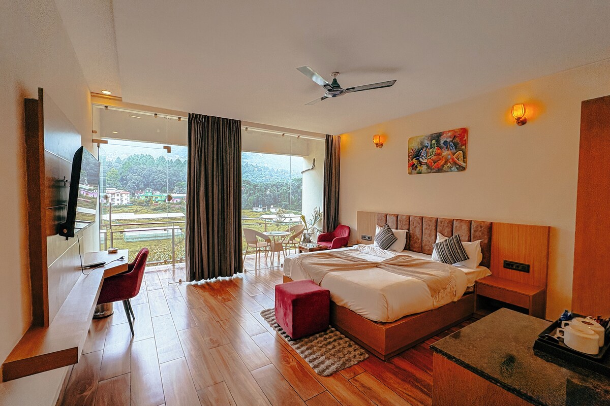 A hotel room with a bed, a desk, a chair, a television, and a view of the outdoors.